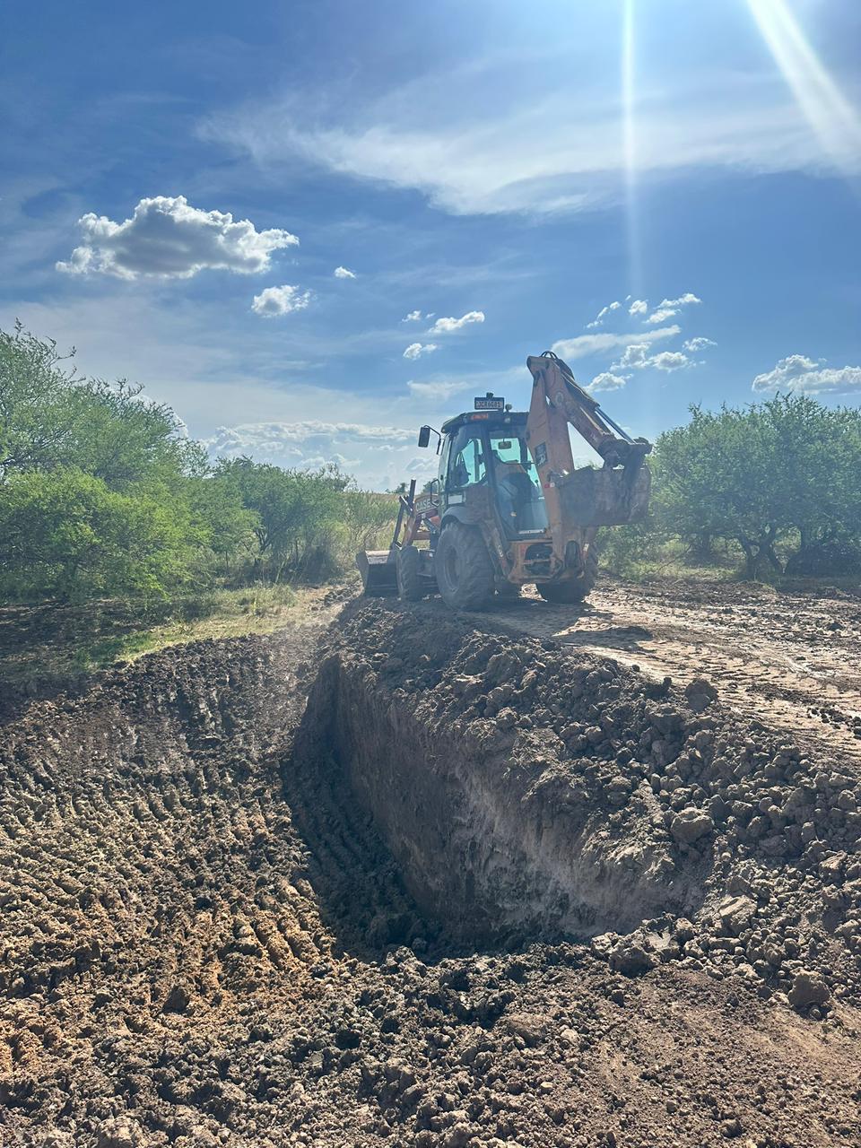 Terraplanagem — retroescavadeira movimentando terra em área rural