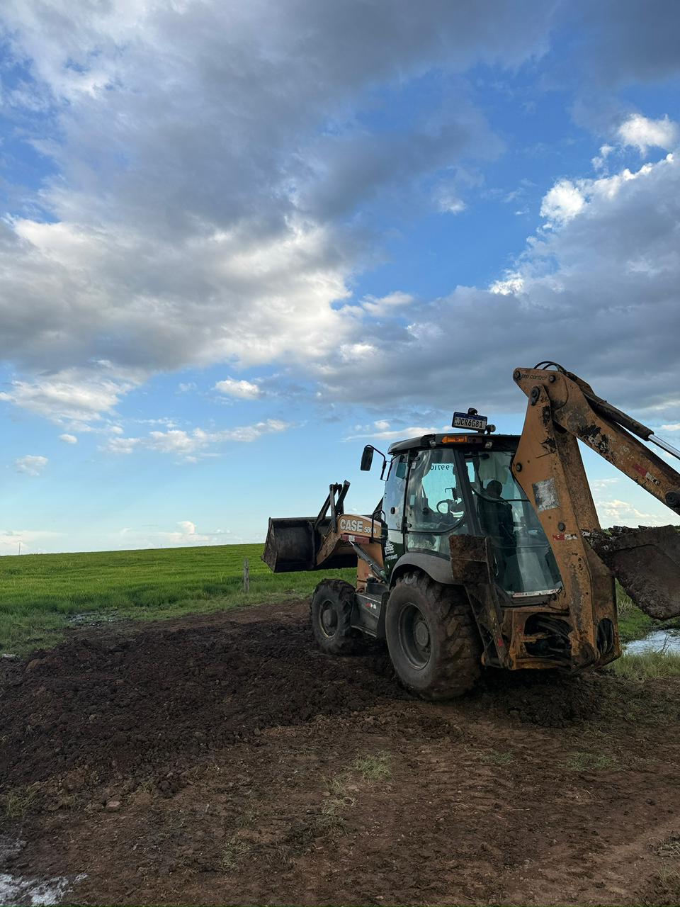 Construção de açude — retroescavadeira escavando leito para acúmulo de água
